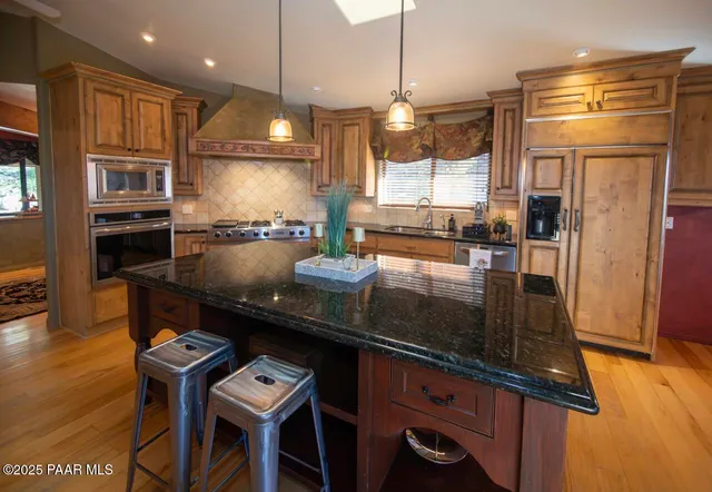 a kitchen with stainless steel appliances granite countertop a sink a stove and a refrigerator
