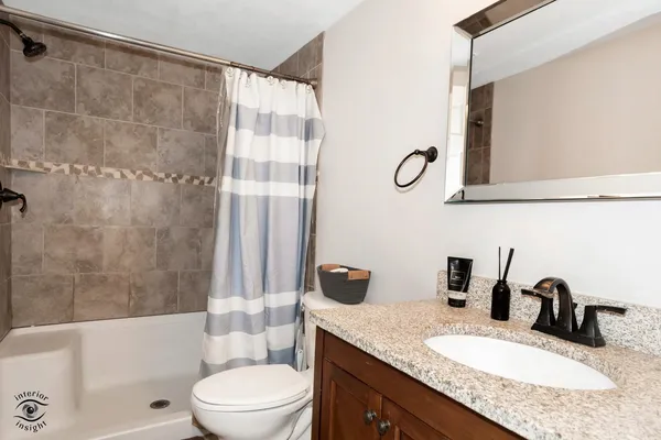 a bathroom with a granite countertop sink a toilet and a bathtub