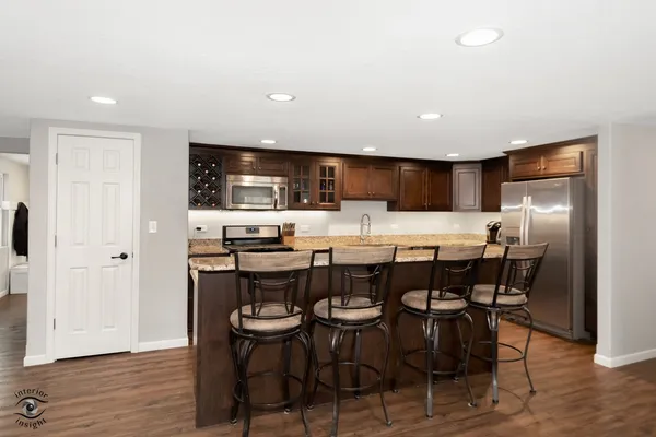 a kitchen with stainless steel appliances a dining table chairs refrigerator and microwave