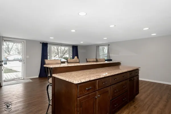 a dining hall with stainless steel appliances granite countertop a stove and a sink