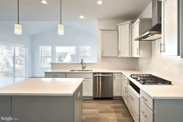 a kitchen with stainless steel appliances a sink a stove a refrigerator cabinets and a window