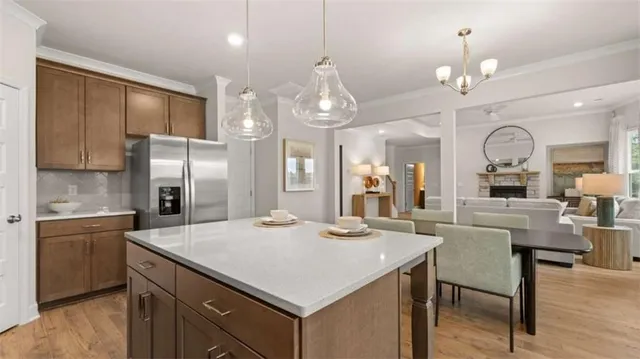 a kitchen with stainless steel appliances kitchen island granite countertop a sink a refrigerator and chairs