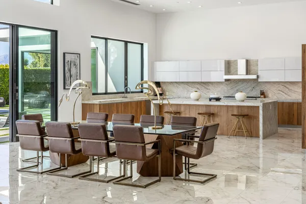 a view of kitchen with stainless steel appliances granite countertop table chairs and a view of living room