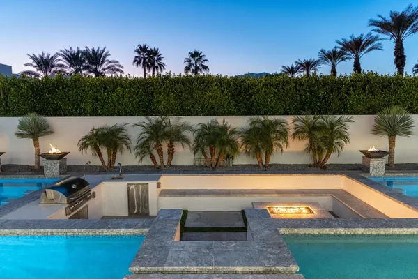 a view of swimming pool with seating area and trees in the background