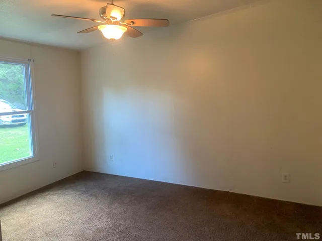 an empty room with a window and a fan
