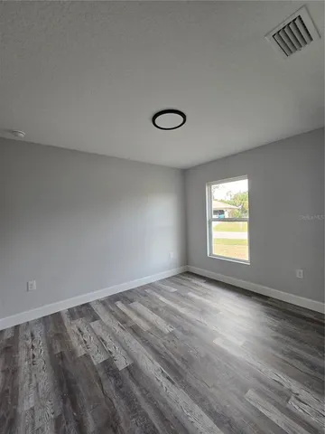 a view of an empty room with a window and wooden floor