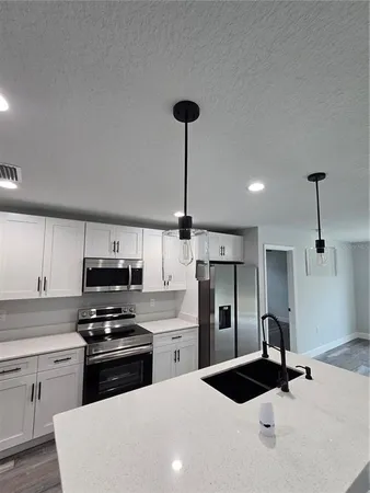 a kitchen with kitchen island a counter space a sink a stove and refrigerator