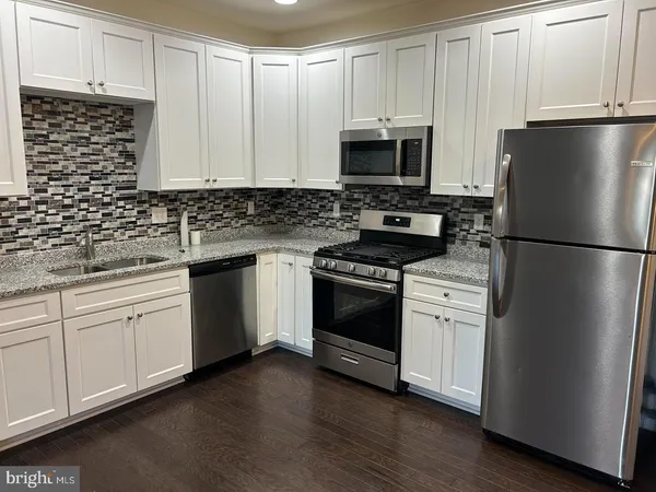 a kitchen with white cabinets white stainless steel appliances and sink