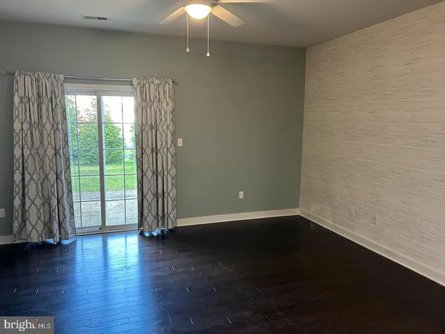 an empty room with wooden floor and windows with curtains