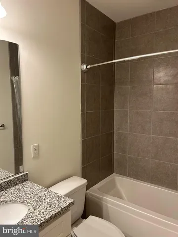 a bathroom with a granite countertop bathtub shower and toilet