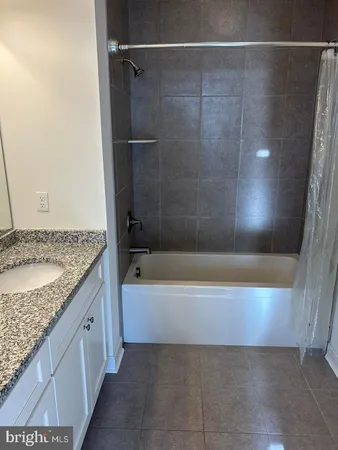 a bathroom with a granite countertop sink and a bathtub