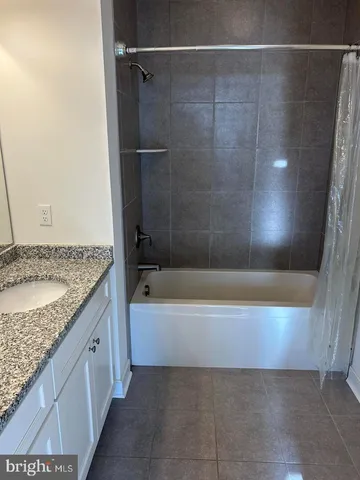 a bathroom with a granite countertop sink and a bathtub