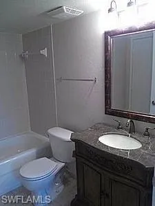 a bathroom with a granite countertop toilet sink and mirror