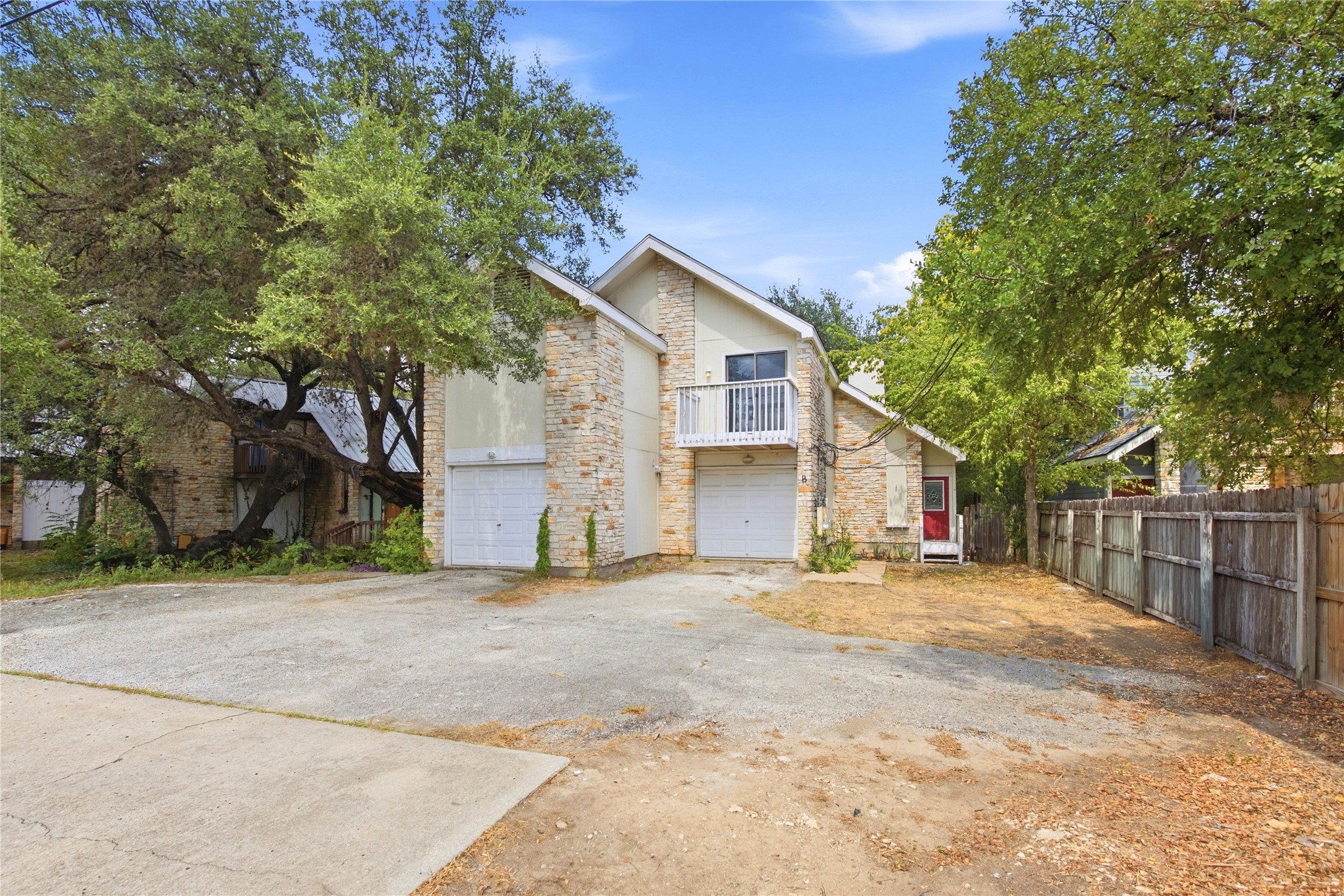 2500 Jones Road, Unit B Austin, TX 78745 - Photo 13 of 37 Mature trees shade a stone-accented duplex exterior with private garage parking.