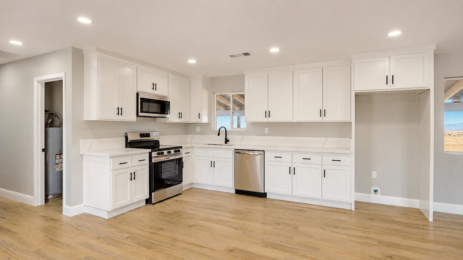 4728 Zorro Road La Grange, CA 95329 - Photo 20 of 56 Modern kitchen featuring white cabinetry, light-toned countertops, stainless steel appliances, and wood-finish flooring