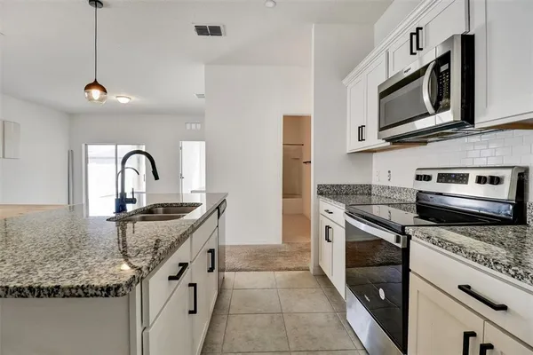 a kitchen with stainless steel appliances granite countertop a sink a stove a refrigerator and window