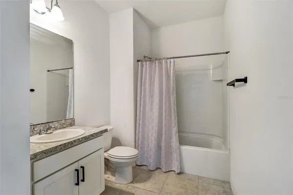 a bathroom with a granite countertop sink a toilet mirror and a vanity