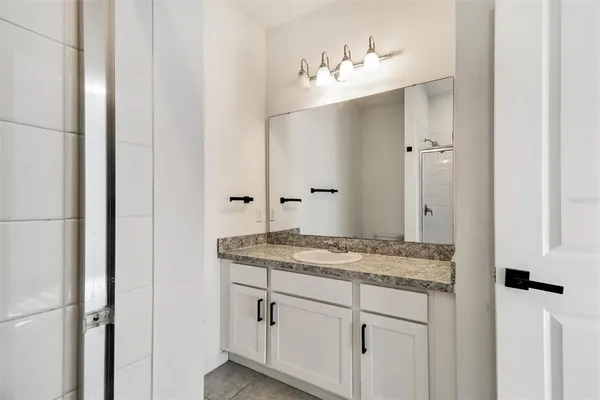 a bathroom with a granite countertop sink and a mirror