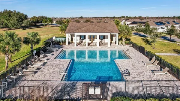 a view of swimming pool with outdoor seating and trees in the background