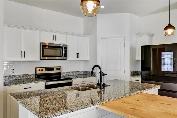 a kitchen with stainless steel appliances granite countertop a stove a sink and a microwave