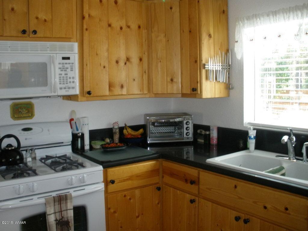 2135 Wildflower Road Overgaard, AZ 85933 - Photo 23 of 44 a kitchen with granite countertop a sink stove and cabinets