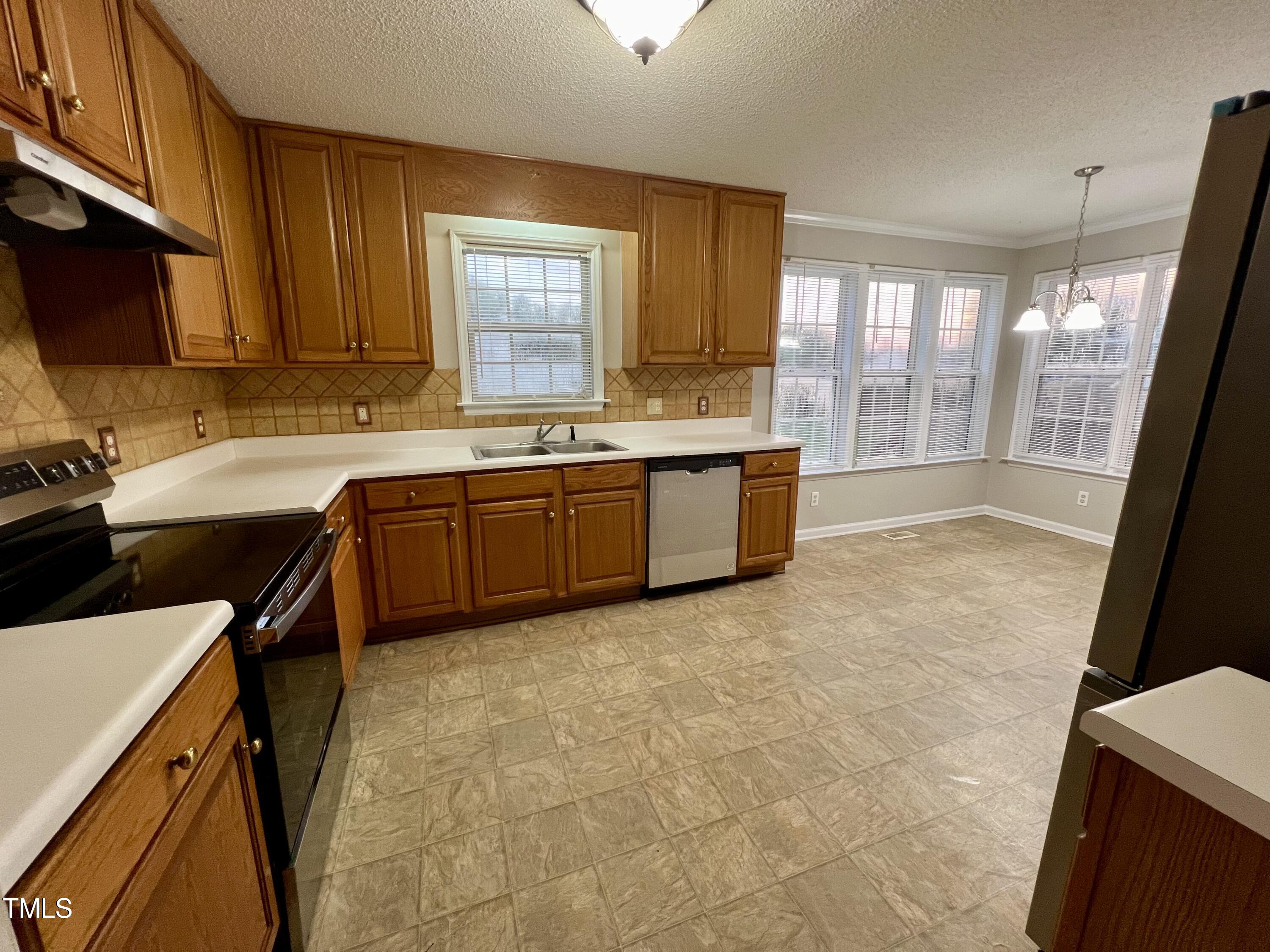 1312 Harvey Johnson Road Raleigh, NC 27603 - Photo 12 of 29 a large kitchen with a stove a sink dishwasher a microwave oven and a dining table with wooden cabinet