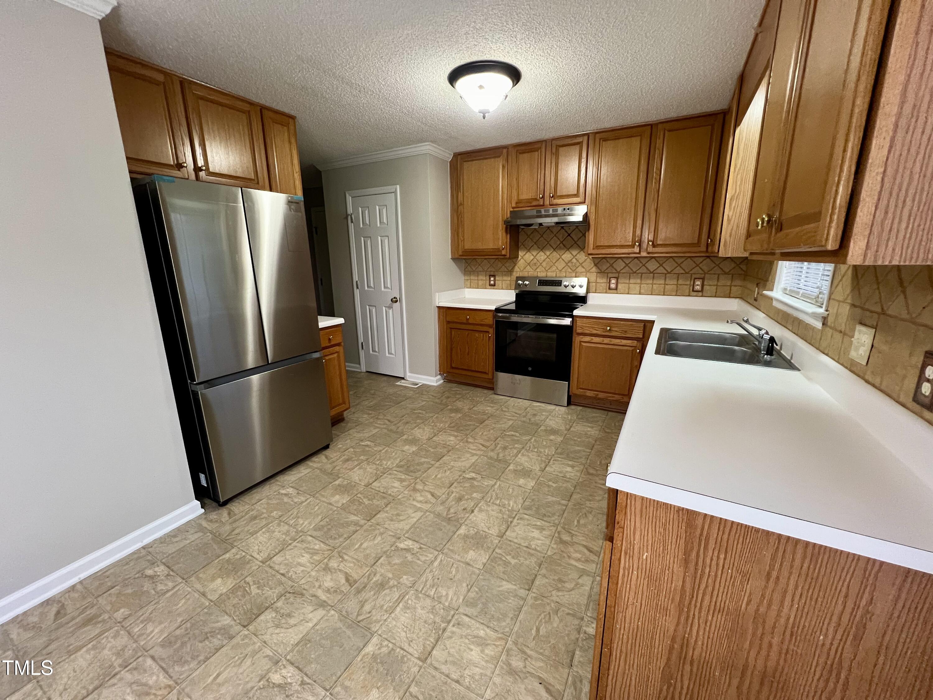 1312 Harvey Johnson Road Raleigh, NC 27603 - Photo 10 of 29 a kitchen with granite countertop a refrigerator sink and wooden cabinets