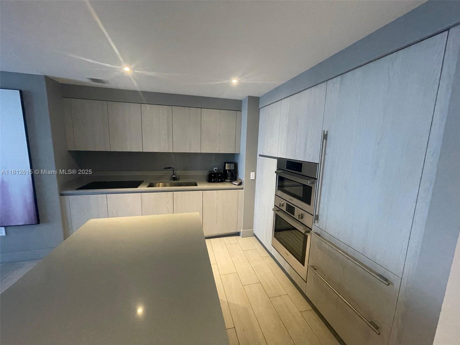 4010 South Ocean Drive, Unit R1705 Hollywood, FL 33019 - Photo 6 of 15 a large kitchen with white cabinets and stainless steel appliances