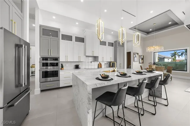 a large white kitchen with kitchen island a large counter top space a sink stainless steel appliances and cabinets