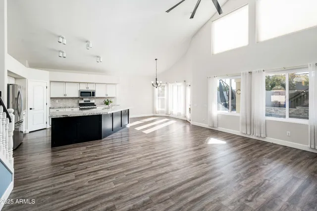 a large kitchen with stainless steel appliances kitchen island a large counter top and a wooden floor