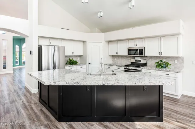 a kitchen with stainless steel appliances granite countertop a sink a stove a microwave a center island and cabinets