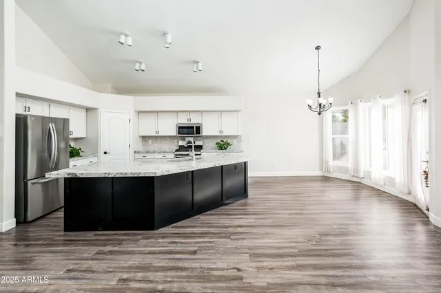 a kitchen with stainless steel appliances kitchen island granite countertop a sink stove and refrigerator