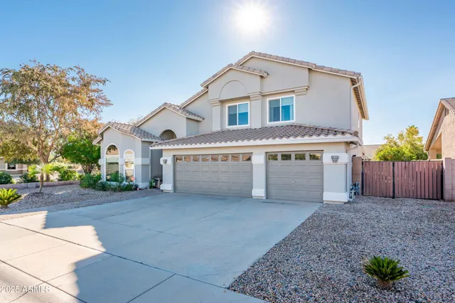 a view of a white house next to a yard with potted plants