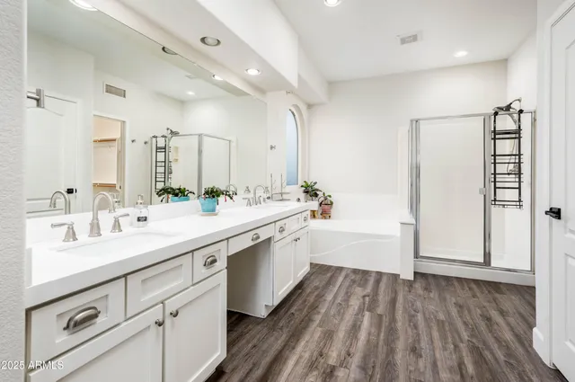 a large white bathroom with a double vanity sink a mirror and a bathtub