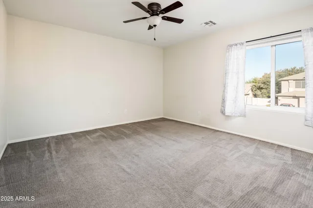 an empty room with windows and fan