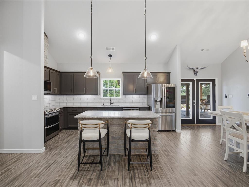 117 Ranchview Court Bowie, TX 76230 - Photo 11 of 40 a kitchen with stainless steel appliances a table chairs stove and kitchen island