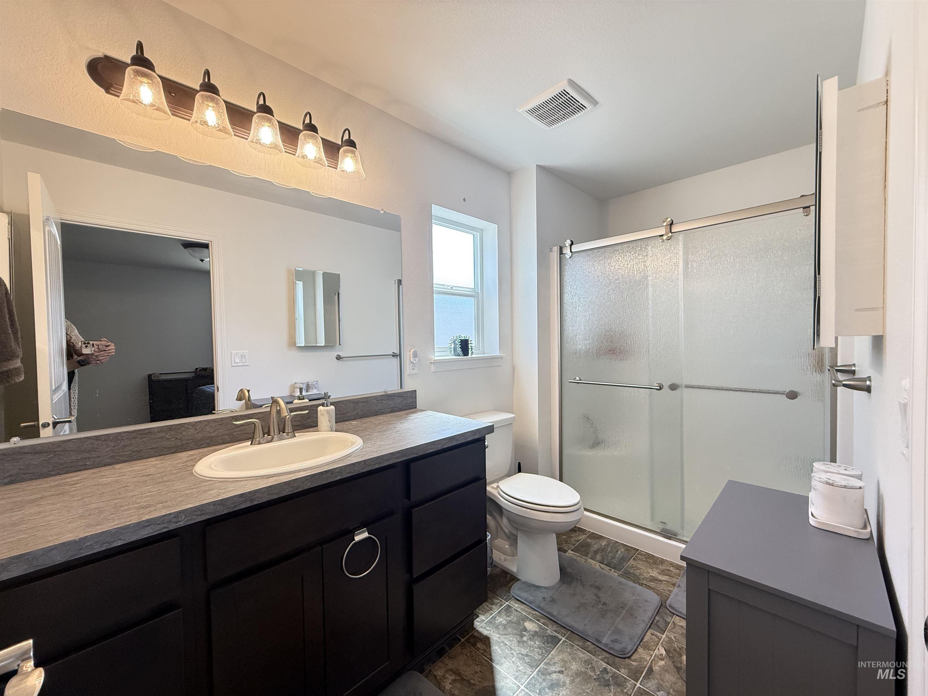 1556 Frontier Drive Lewiston, ID 83501 - Photo 9 of 23 Bathroom featuring a dark wood-finish vanity with an integrated sink, a large mirror, and a five-light fixture