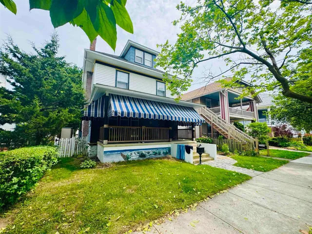 a view of a house with a yard deck and a large tree