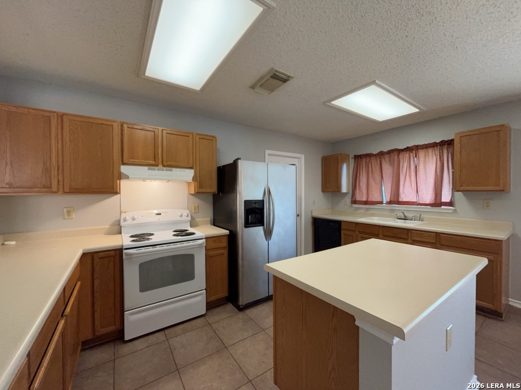 7322 Raintree Forest San Antonio, TX 78233 - Photo 14 of 40 a kitchen with a stove a sink dishwasher and a refrigerator