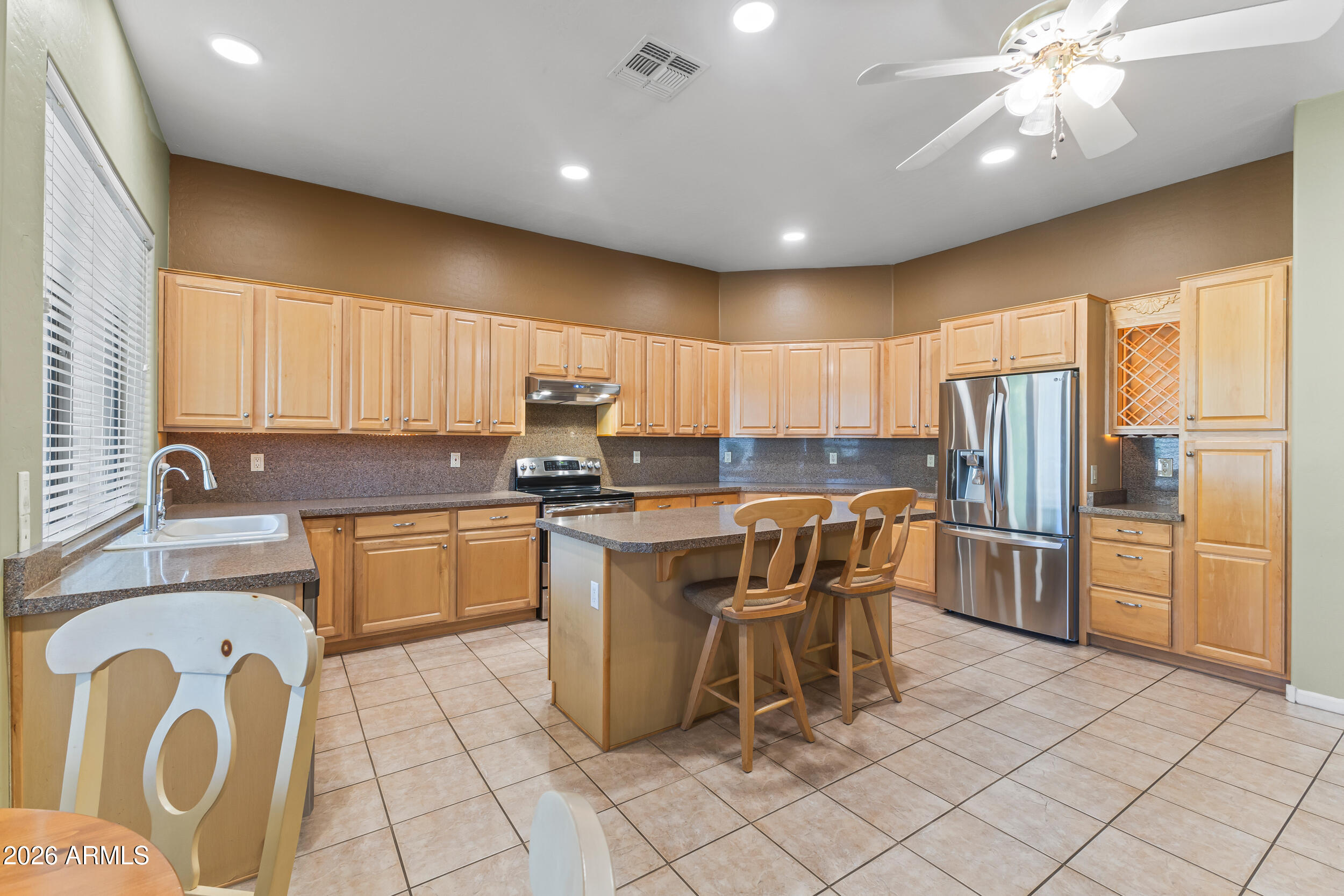 584 South Granite Street Gilbert, AZ 85296 - Photo 23 of 49 a kitchen with stainless steel appliances granite countertop a refrigerator a sink dishwasher a dining table and chairs with wooden floor