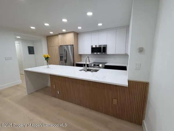 a kitchen with kitchen island sink and refrigerator