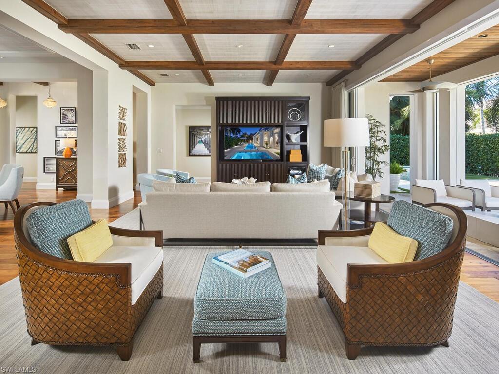 631 Broad Court North Naples, FL 34102 - Photo 7 of 23 a living room with couches a fireplace and a dining table with wooden floor