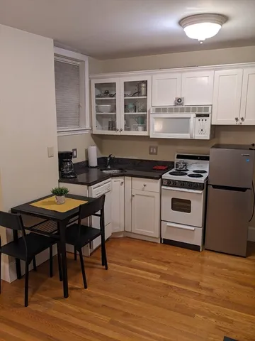 a kitchen with a stove a sink and wooden floor