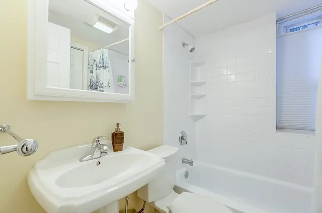 a white bath tub sitting next to a white sink and vanity