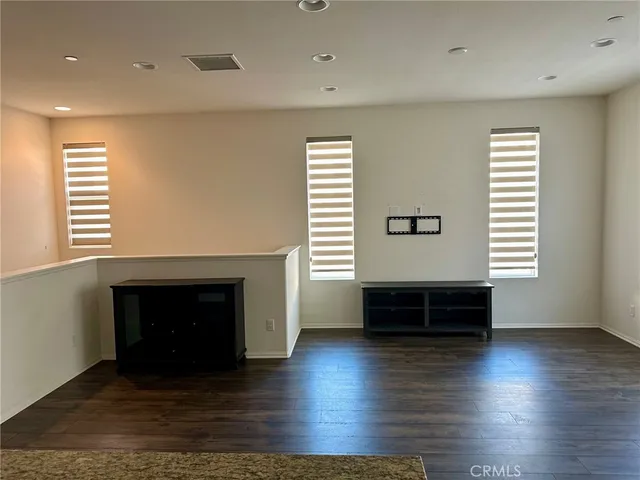 an empty room with wooden floor a fireplace and windows