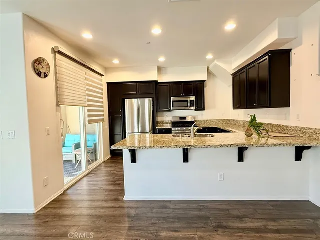a view of kitchen with stainless steel appliances granite countertop a stove and a sink