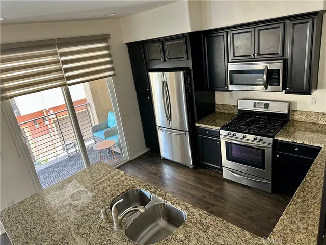 a kitchen with granite countertop a refrigerator stove and sink