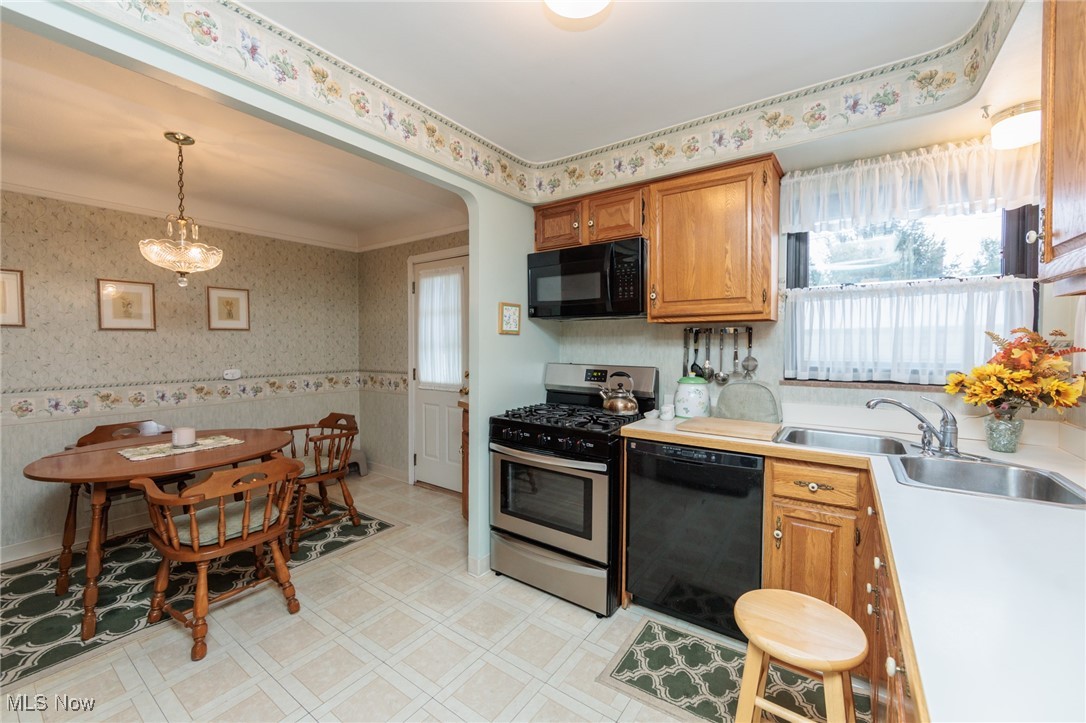 6192 Stanbury Road Parma, OH 44129 - Photo 26 of 49 Kitchen featuring wallpapered walls, black appliances, healthy amount of natural light, light countertops, and brown cabinets