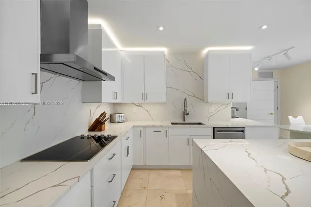 a kitchen with a sink dishwasher and white cabinets with wooden floor