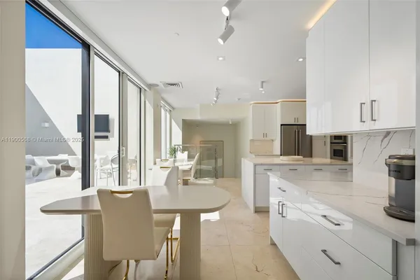 a kitchen with stainless steel appliances granite countertop a table chairs and a refrigerator